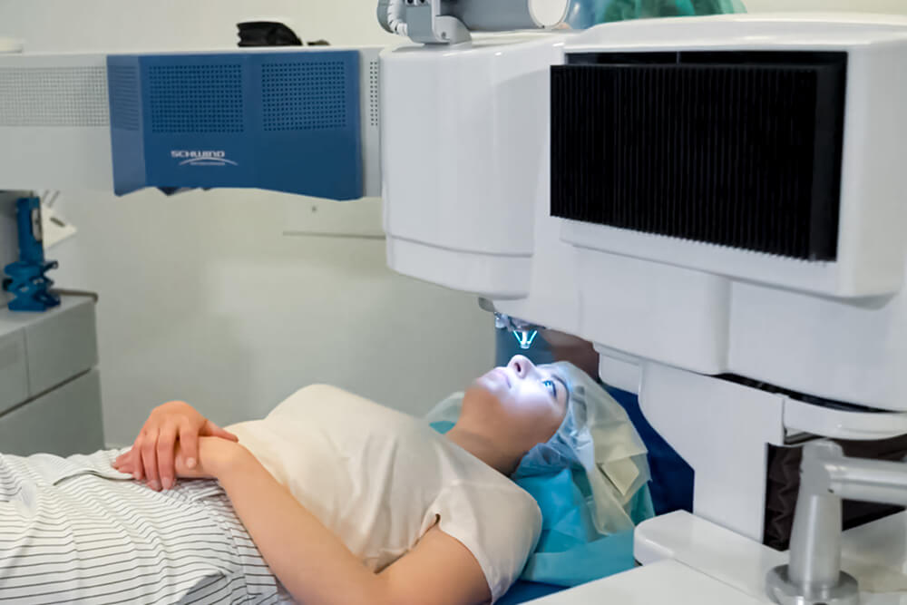 Frau liegt unter einem Augenlasergerät, das auf ihr geöffnetes Auge ausgerichtet ist