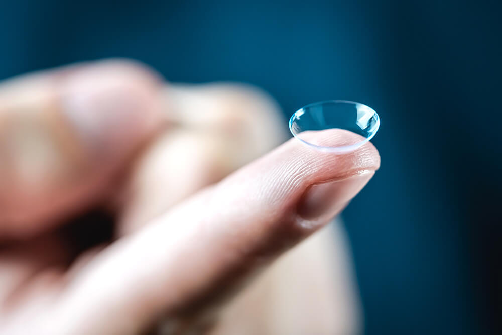 Nahaufnahme eines Fingers, auf dem eine transparente Kontaktlinse liegt