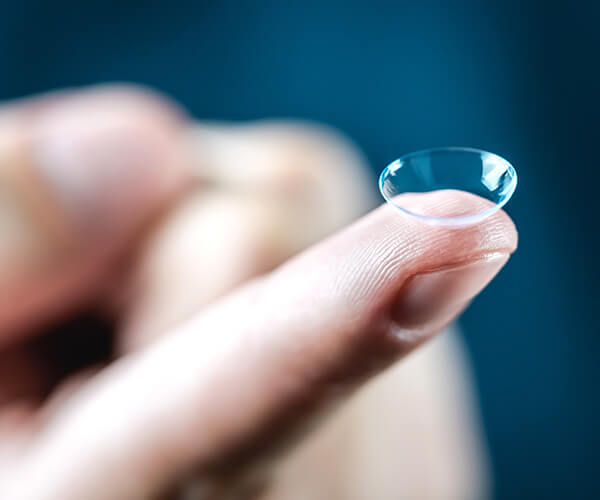Nahaufnahme eines Fingers, auf dem eine transparente Kontaktlinse liegt